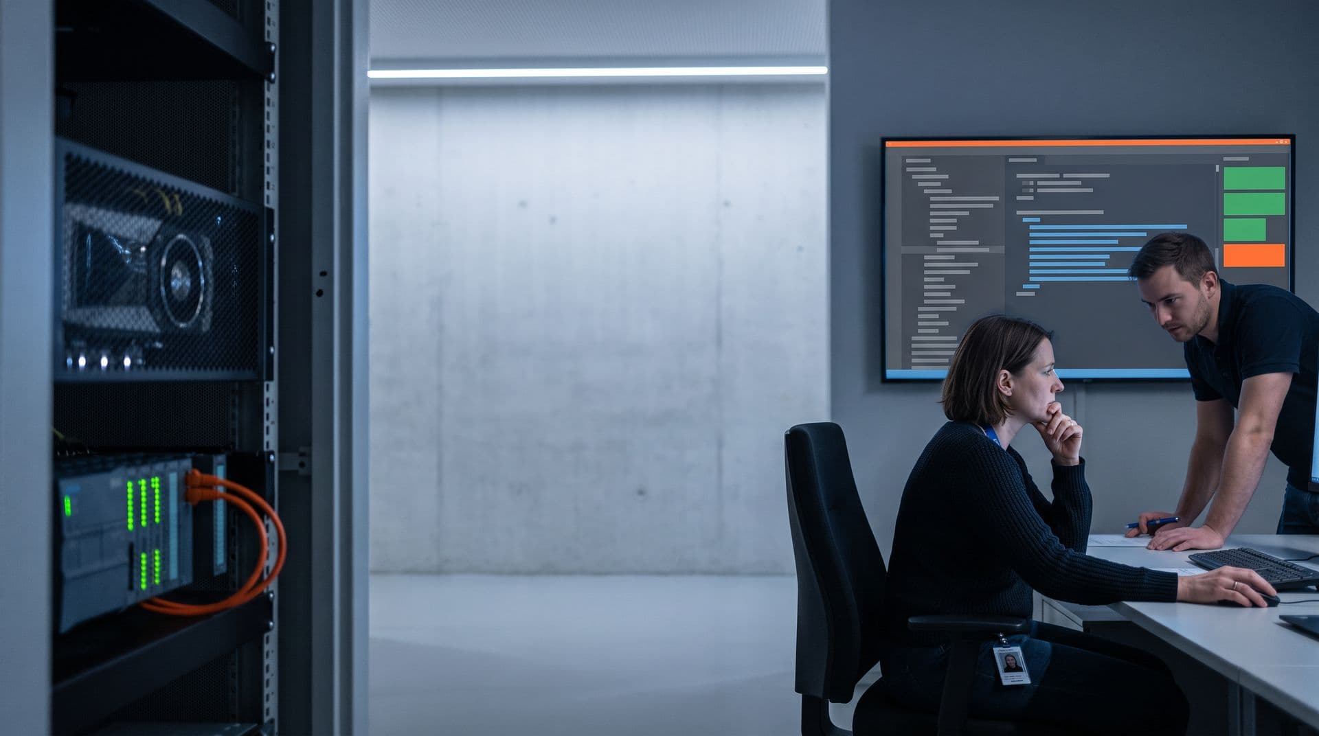 Links ein Gestell mit lokalem KI-Server und Steuerungs-Testaufbau, rechts zeigt ein Wandbildschirm einen KI-Codevorschlag in Blau neben der Prüfkette; eine Steuerungstechnikerin liest ihn, ein Kollege beugt sich zu ihr